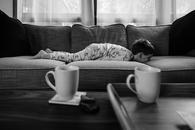 black and white young boy lays face down on couch 