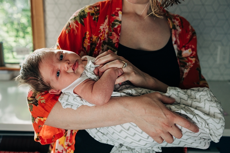 newborn baby makes eye contact with camera in kitchen 