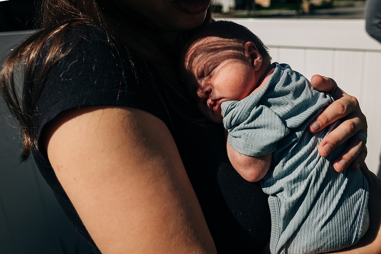 Newborn girl sleeps vertically against mother's chest
