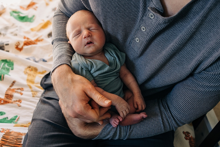 Top down: newborn baby sleeps peacefully in her father's arms