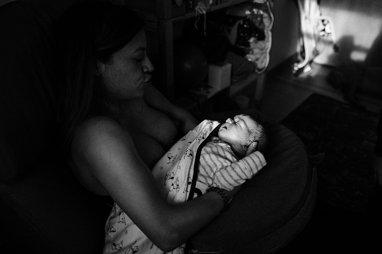 dramatic light focuses on winter newborn bundled in cozy blanket in mother's arms 