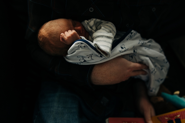 soft winter light highlights a newborn's small fist while being swaddled in a cozy blanket 
