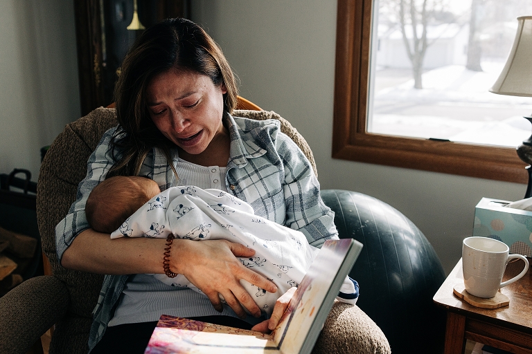 Tearful mother reads an emotional book to her newborn winter baby