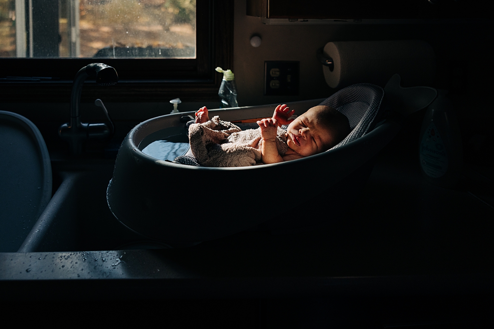 Newborn gets first bath in beautiful autumn light coming through the kitchen window