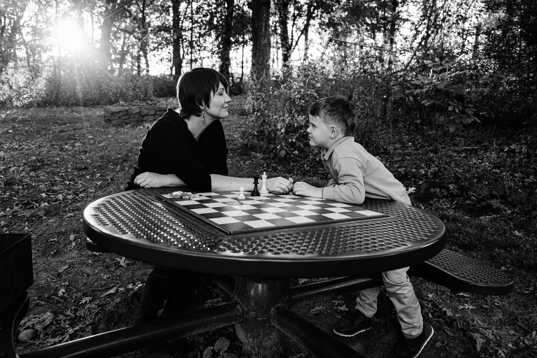 mother plays chess in the park with her son