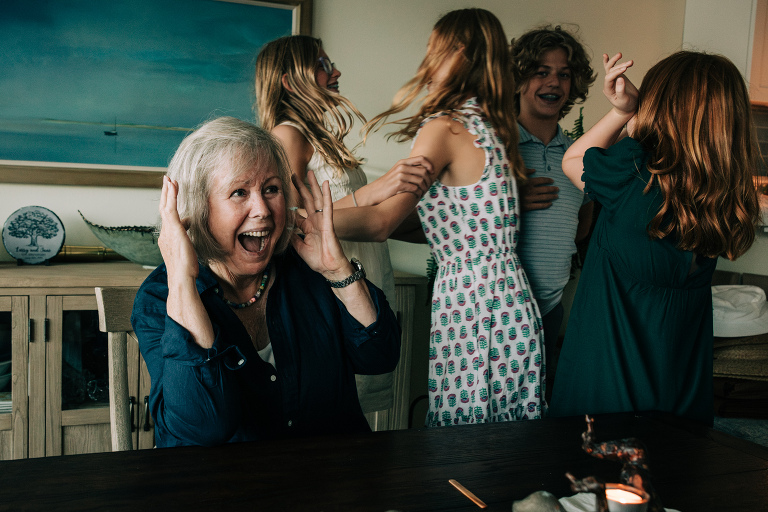 grandmother smiles and covers her ears from screaming, happy grandchildren