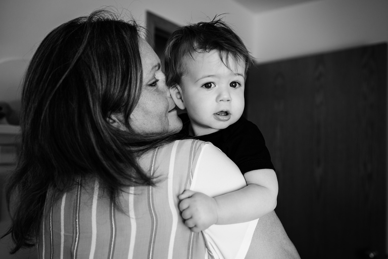 grandmother kisses one year old on the ear, boy is smiling