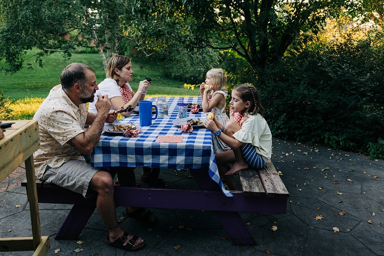 Family eats dinner outside together on end of summer night