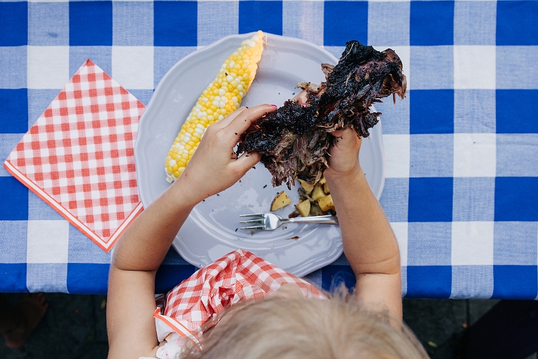 Girl separates rib meat from bone with her hands in top down shot