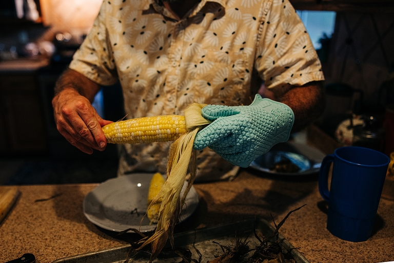 Father shucks corn on late summer night
