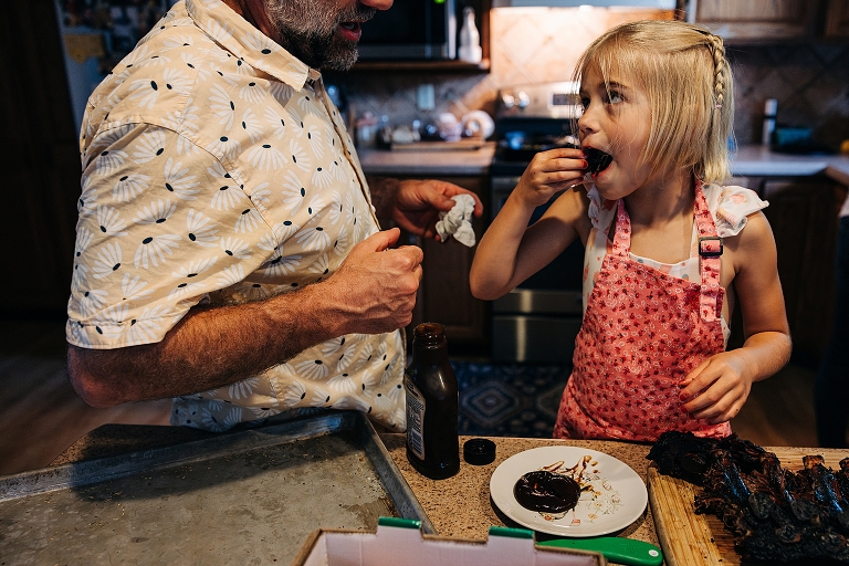 Young daughter tastes pork rib with barbecue sauce