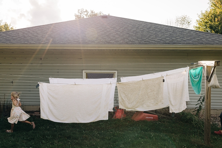 Young girl runs by hanging laundry on late summer night