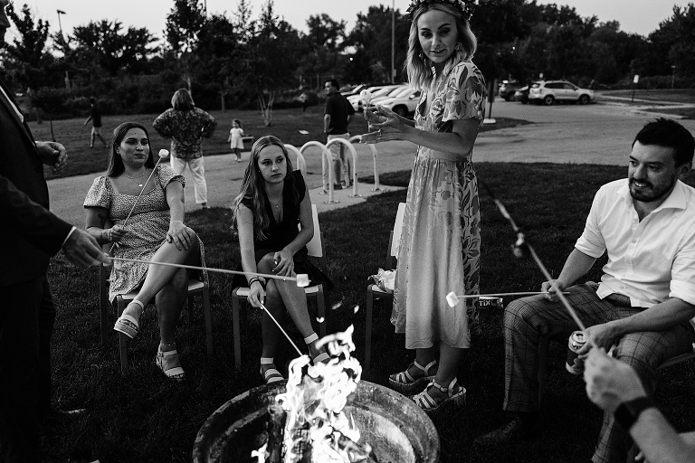 Black and white: wife talks as guests roast marshmallows in fire pit