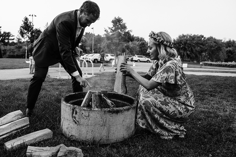 Black and white: Wife and man prepare fire pit for evening festivities 