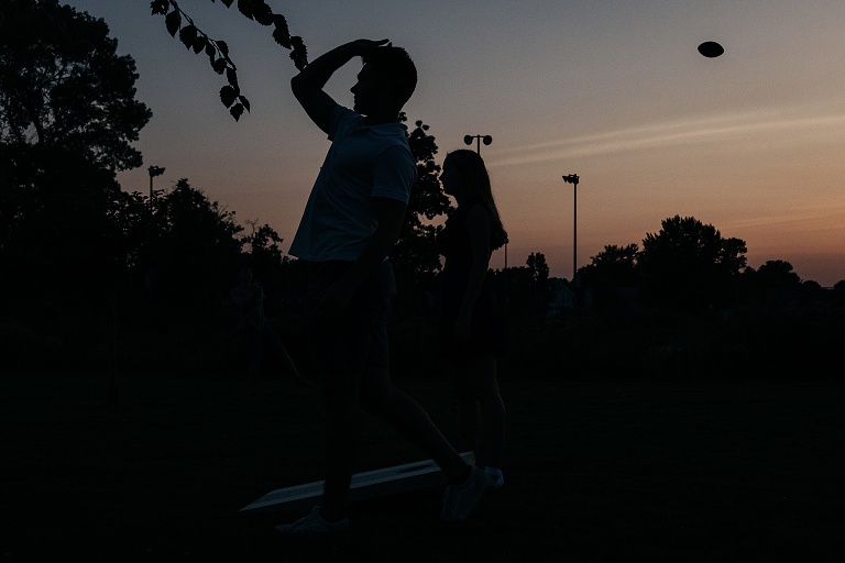 Two figures look out into the dusk with a football flying behind them after Tenney Park wedding