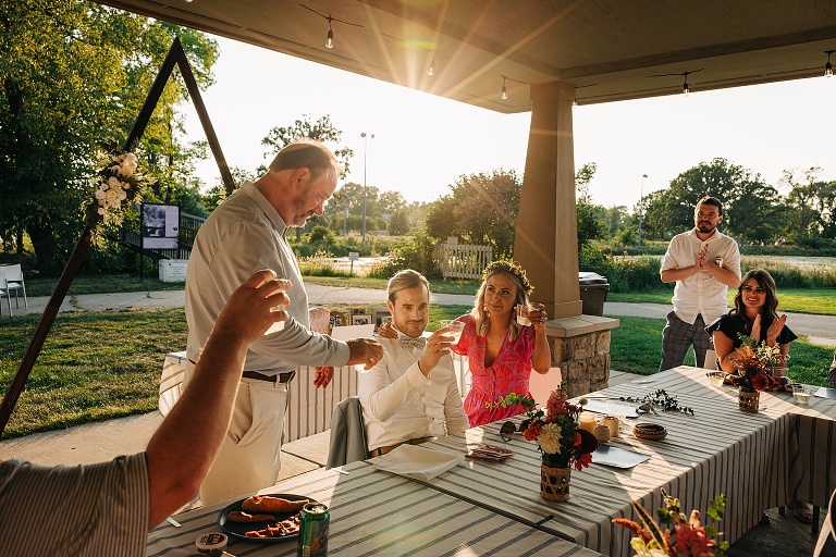 Guests and newly weds applaud and raise glasses after man's toast at Tenney Park Documentary Wedding reception