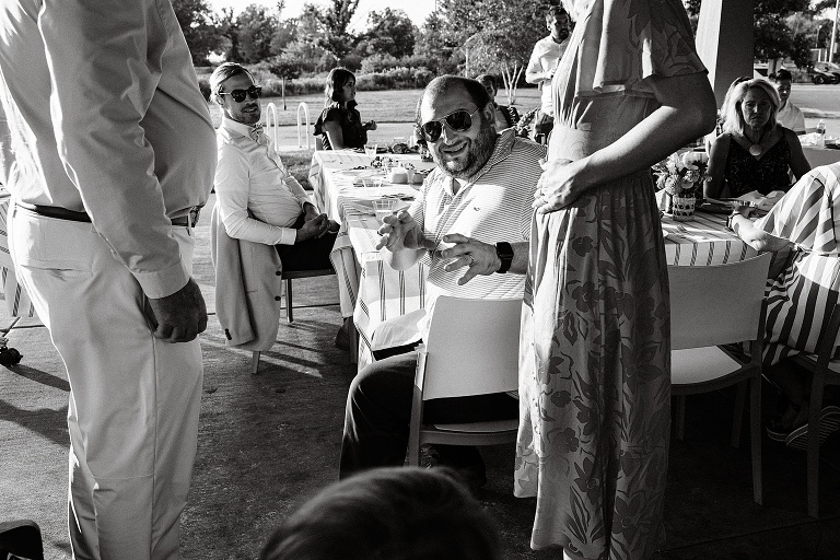 Black and white: guests and husband converse at Tenney Park Documentary Wedding reception