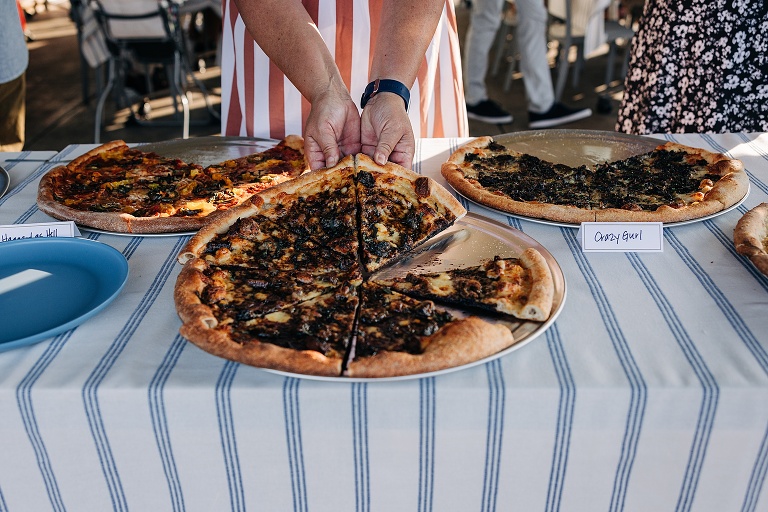 A woman separates piece of vegetable topped pizza for herself