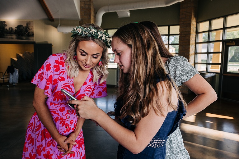 Flower Girl shows bride something on her phone at Tenney Park Documentary Wedding