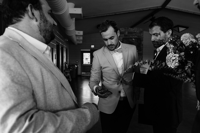 Black and white: men wait with groom before start of Tenney Park Documentary Wedding ceremony