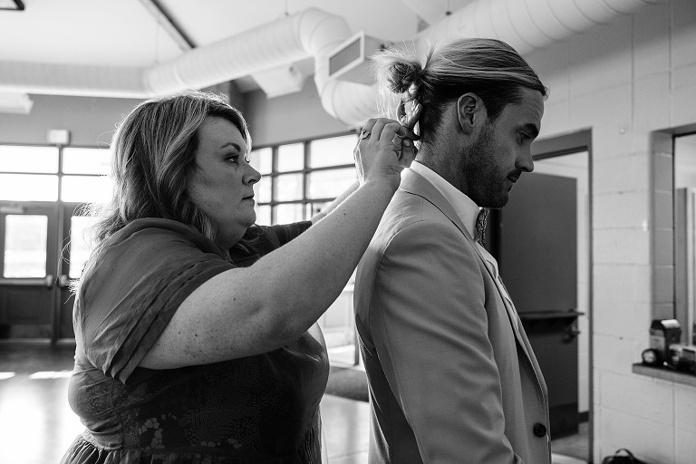 Woman helps groom with his hair before Tenney Park Documentary Wedding