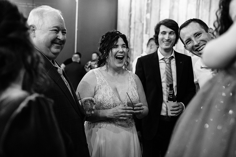 Bride and groom laugh with four other guests after fall wedding at home