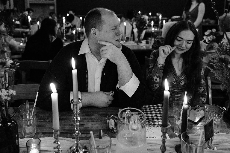 Male guest jokes with female guest at restaurant with lit candles and empty glasses in the foreground