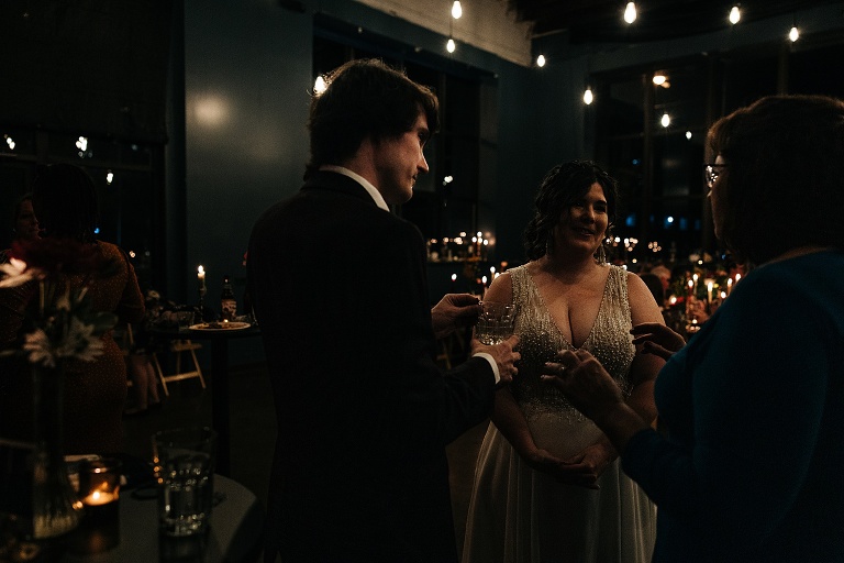 Man converses with husband and wife at the restaurant after the fall wedding at home