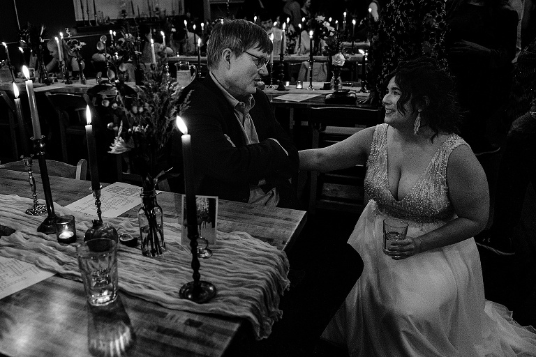 Black and white: Wife converses with older male guest at the restaurant ignited by many candles