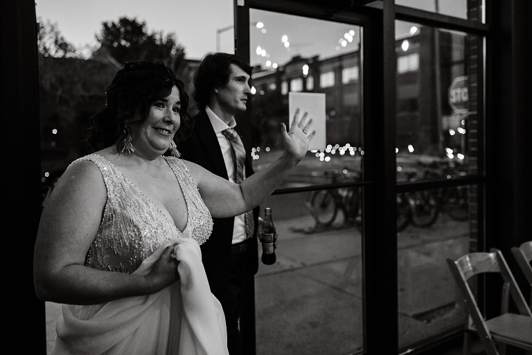 Black and white: wife greets server by waving as the newly wed couple walk into the restaurant