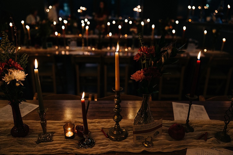 Flower bouquet and candles inside the dimly lit fancy restaurant, more candles illuminate the background 