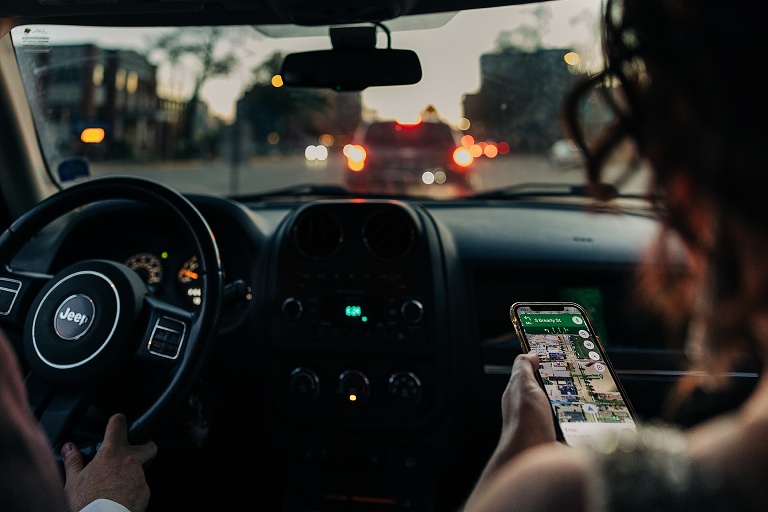 Wife navigates google maps while husband drives Jeep with braking truck in the background 