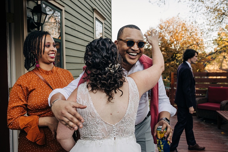 Wife embraces male and female guests with husband in the background