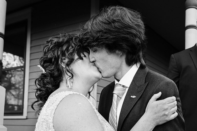 Black and white: the bride and groom kiss concluding the Fall Wedding At Home ceremony