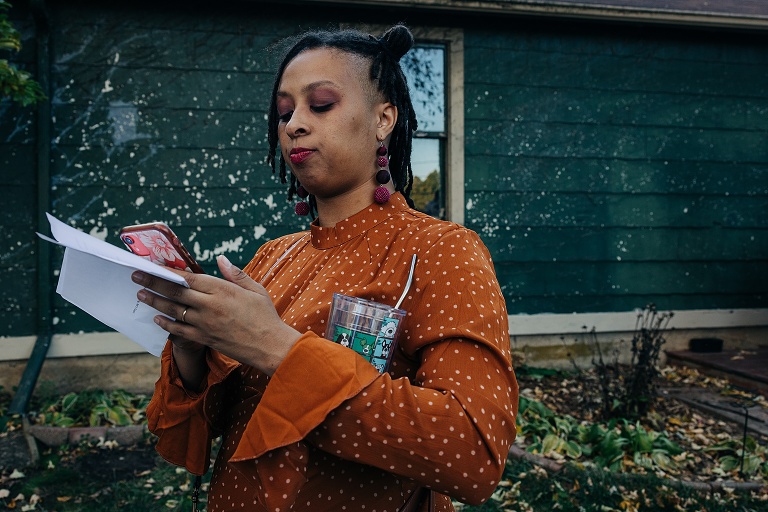 Guest wearing orange dress scrolls her phone before wedding
