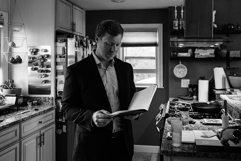 Black and white: man reads notebook in the kitchen of the home
