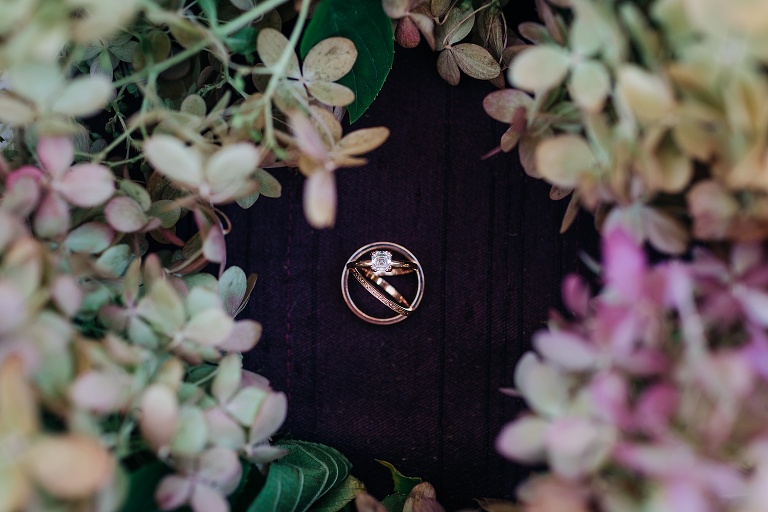Top down: the wedding rings sit surrounded by hydrangea flowers before Fall Wedding At Home
