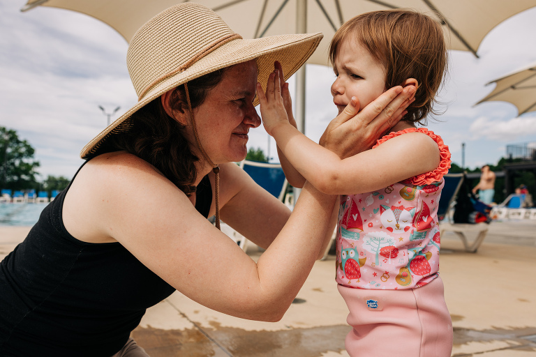 mother and daughter put sun screen on each other at same time